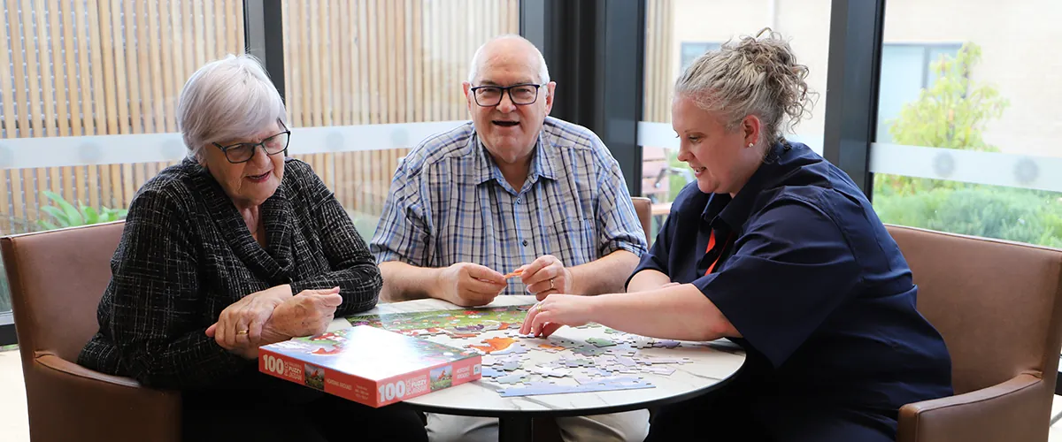 A nurse and two seniors doing a jigsaw puzzle