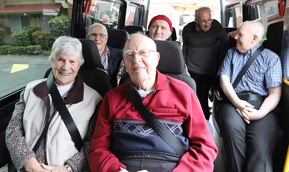 Six Windsor residents sitting on a bus, smiling and looking forward to an adventure.